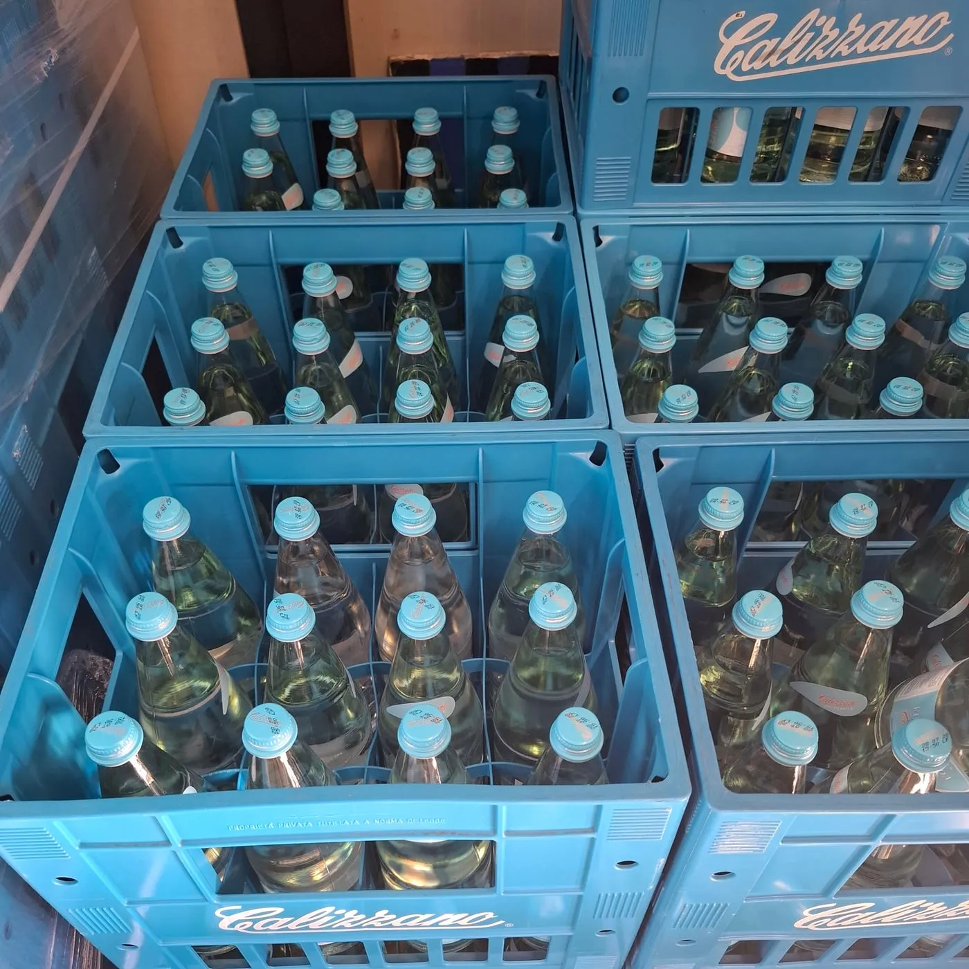Casse azzurre Calizzano piene di bottiglie in vetro, pronte per il giro di consegna