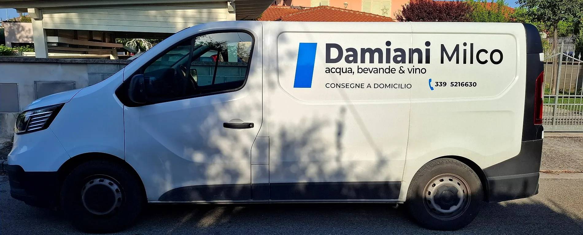 Il furgone bianco di Damiani Milco visto di fianco, con la scritta Damiani Milco, acqua bevande e vino, consegne a domicilio e il numero 339 5216630